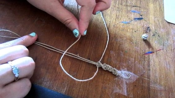 Secure the base thread with the safety pin or a small nail to a stable base. It prevents the thread from shifting when you're making the knots. 